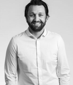 Mørkhåret mand i hvid skjorte på grå baggrund