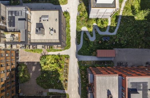 Luftfoto af moderne bygninger, grønne områder og stier i en by.