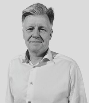 Mand i sort hvid i hvid skjorte på grå baggrund