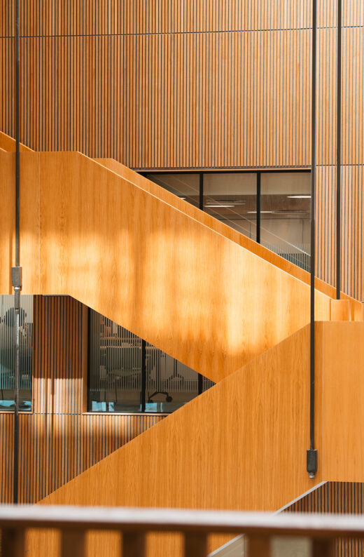 Moderne trætrappe og vægpaneler med lodrette striber i stilfuldt indendørs miljø.