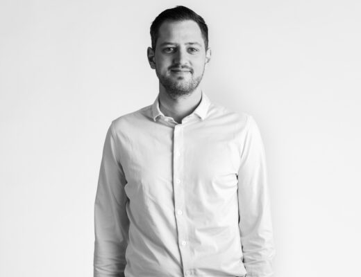 Mand i hvid skjorte står mod hvid baggrund.