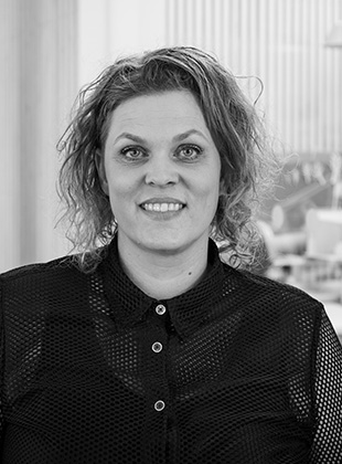 Kvinde i sort bluse med krøllet hår på grå baggrund