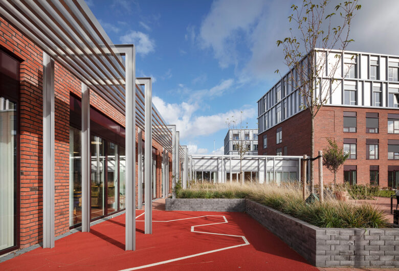 Moderne bygninger med rød mursten og metalarkitektur under blå himmel.