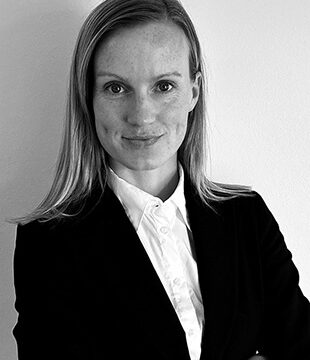 Kvinde i hvid skjorte og sort blazer på grå baggrund