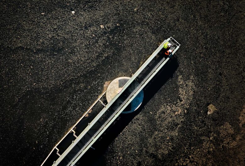 Luftfoto af to arbejdere på gangbro over mudret terræn.