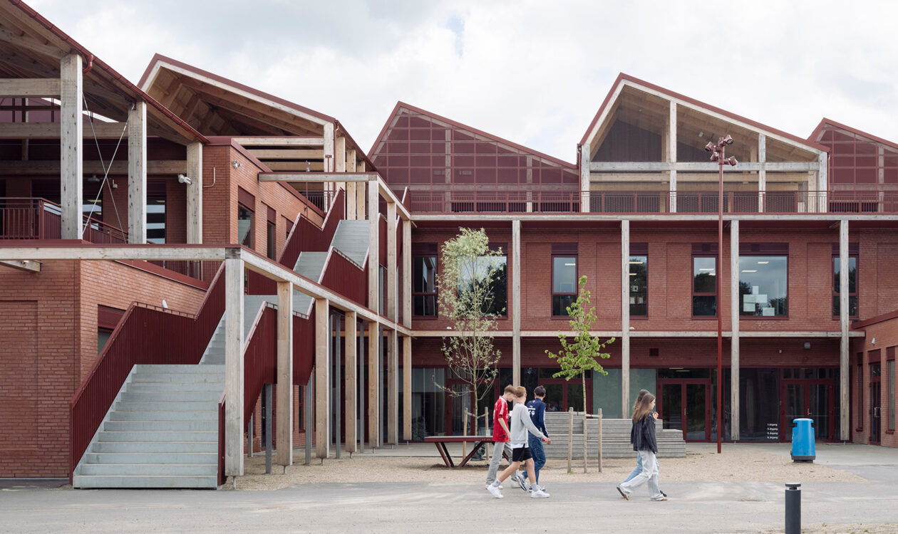 Rød murstensbygning med trinvis trappe og folk, der går udenfor.