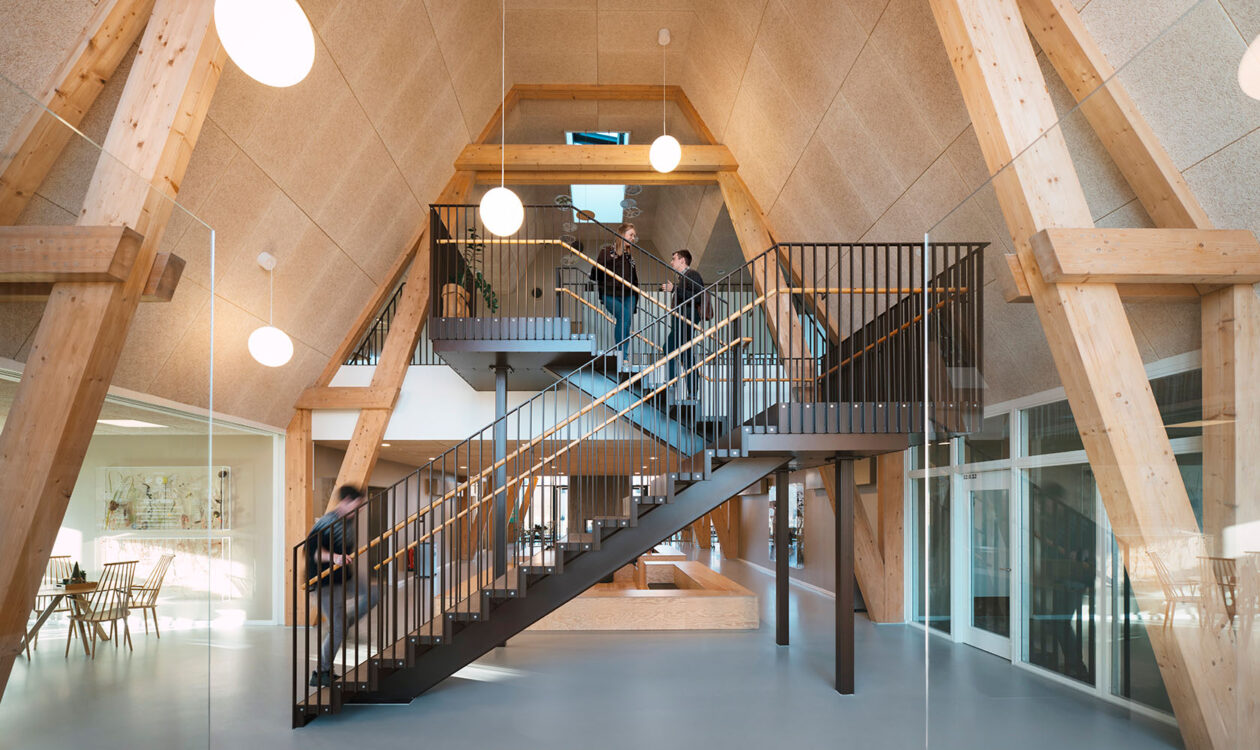 Moderne indendørs kontor med træbjælker og metaltrappe, minimalistisk design med åbne rum.