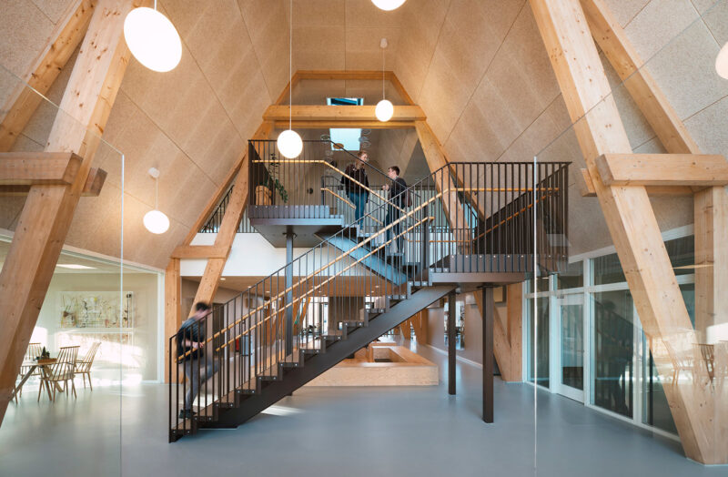 Moderne indendørs kontor med træbjælker og metaltrappe, minimalistisk design med åbne rum.