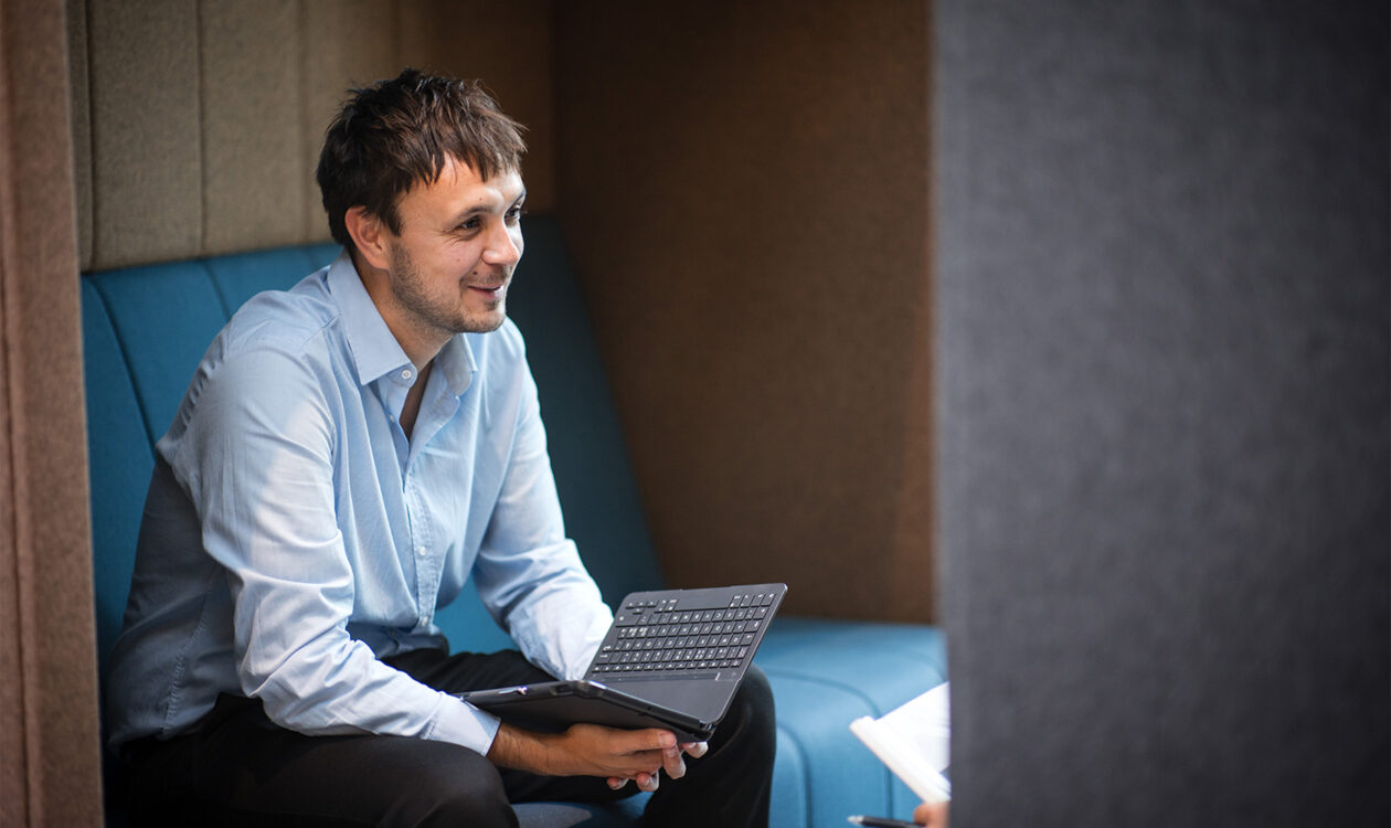 Mand i lyseblå skjorte arbejder på bærbar computer i moderne kontorområde