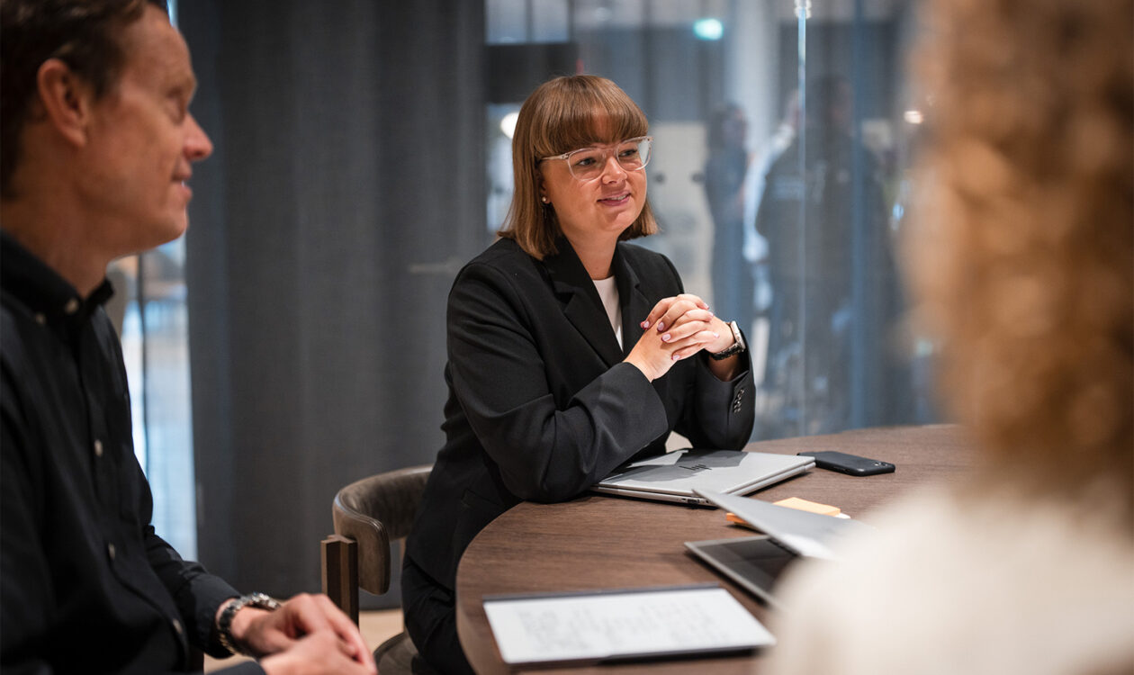 Forretningsmøde ved rundt bord med kontorfolk og laptops