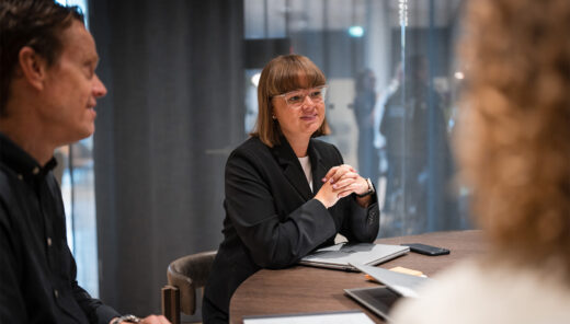 Forretningsmøde ved rundt bord med kontorfolk og laptops