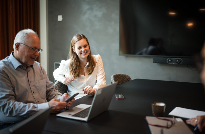 Forretningsmøde i mødelokale med bærbar computer, smartphone og stor skærm
