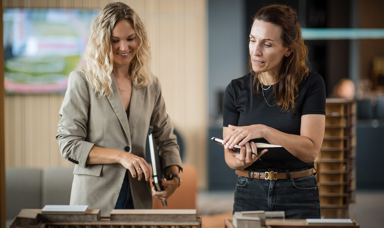 To kvindelige medarbejdere diskuterer byggeprojekt med modeller på kontor